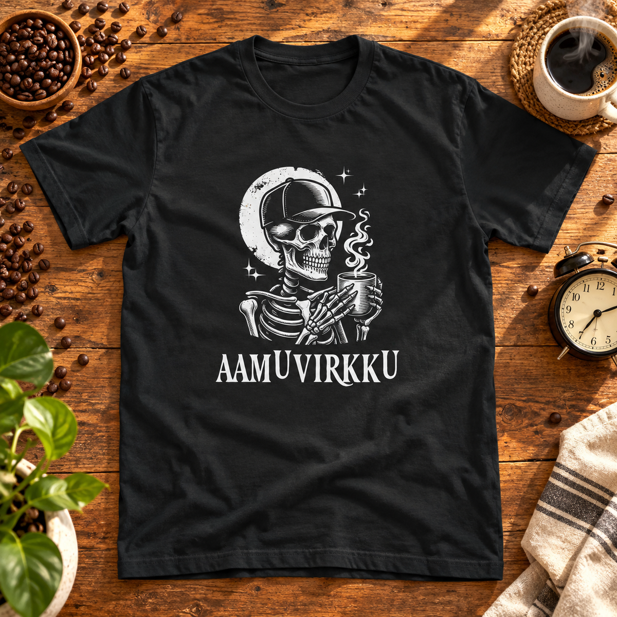 Musta t-paita, jonka printissä lippalakkinen kallo, höyryävä kahvikuppi ja kuu. Printin aiheeseen liittyvä tuotekuva ja rekvisiitta.