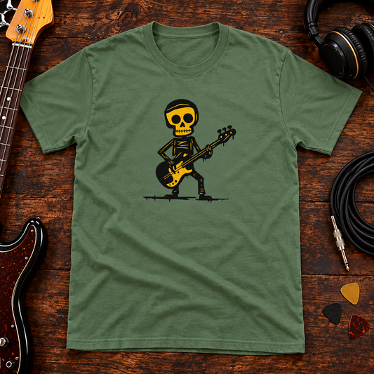 Military green Basisti skeleton bassist T-shirt on a wooden studio table with a bass guitar, instrument cable and headphones.