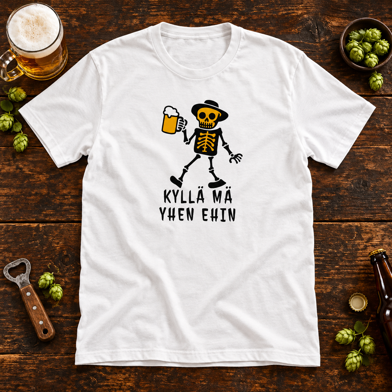 White Kyllä Mä Yhen Ehin T-shirt with a skeleton holding a beer mug on a wooden pub table, surrounded by a foamy beer and hops.