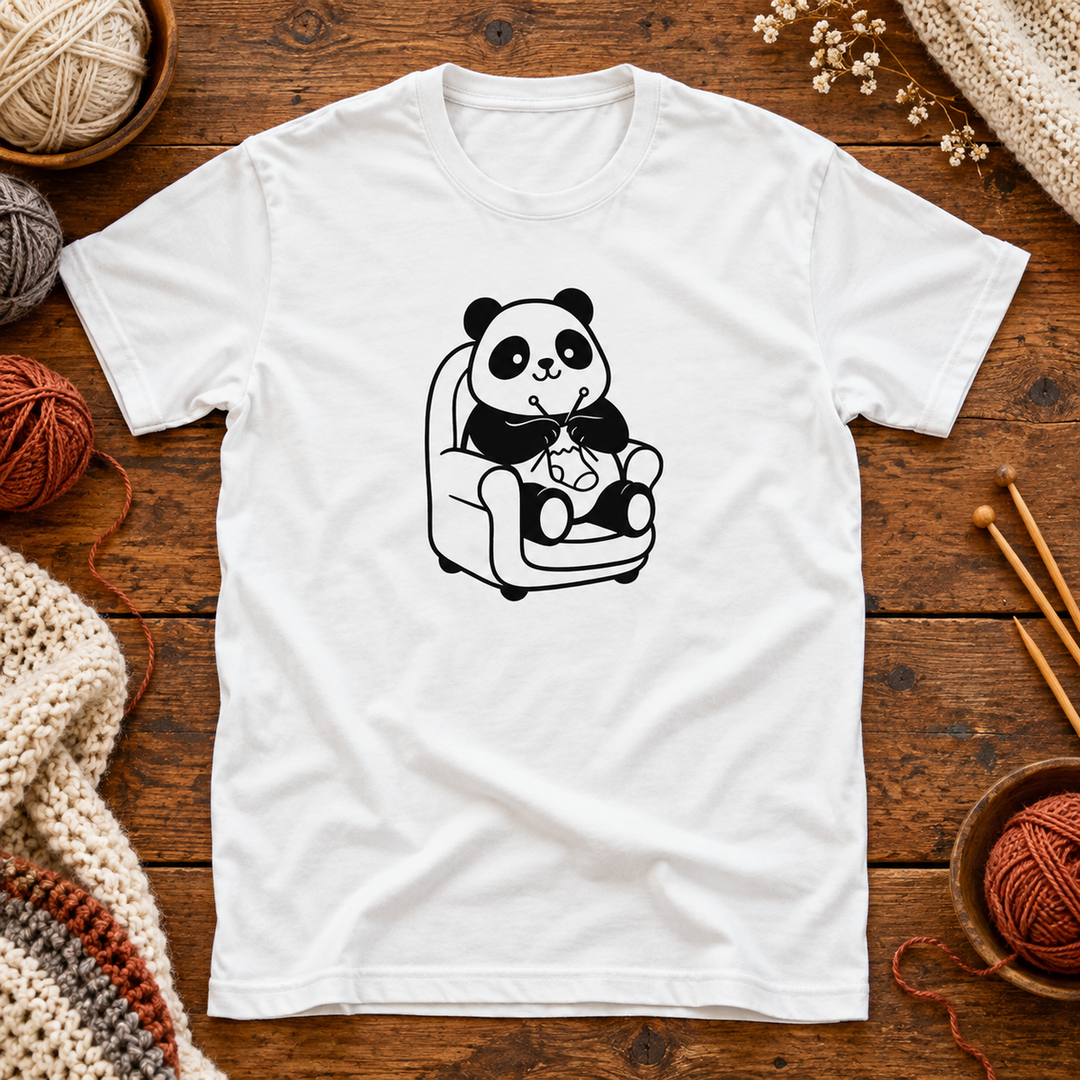T-paita, jonka printissä panda kutoo nojatuolissa.