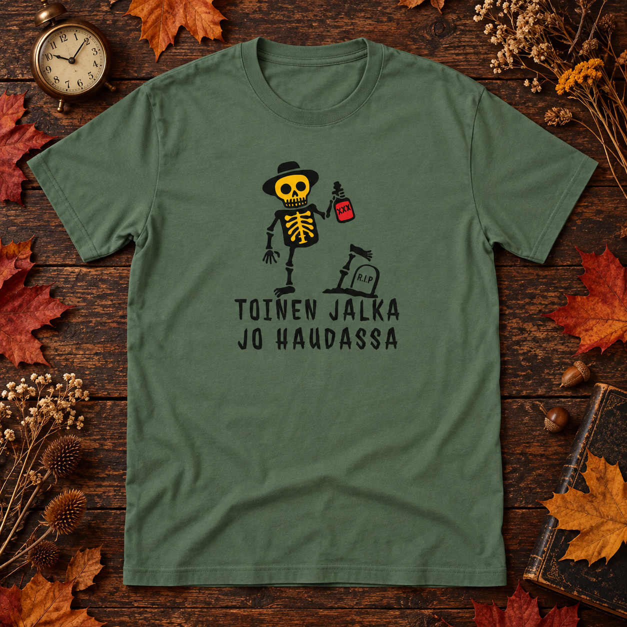 Military green Toinen Jalka Jo Haudassa skeleton print T-shirt on a wooden table with autumn leaves and a vintage clock.