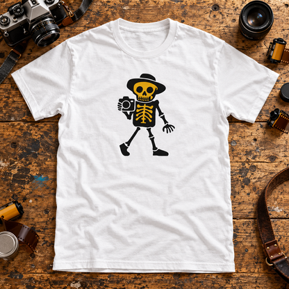 White Valokuvaaja photographer skeleton T-shirt on a wooden table with cameras, lenses and film rolls.