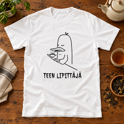 Valkoinen t-paita, jonka printissä teekuppia pitelevä ankka ja TEEN LIPITTÄJÄ -teksti. Printin aiheeseen liittyvä tuotekuva ja rekvisiitta.